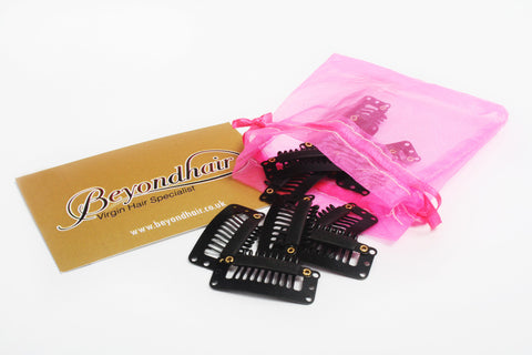 Black hair extension clips in pink organza bag next to beyond hair business card